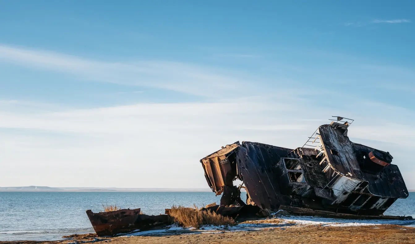 A shipwreck resting on the dried bed of a lake.